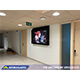 Et 65" ligatursikret TV-kabinet installeret i en gang på en ungdomsinstitution